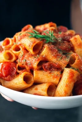 Delicious plate of Arrabbiata Rigatoni topped with fresh herbs and chili flakes.