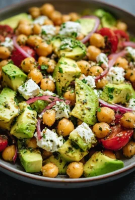 Chickpea feta avocado salad garnished with fresh herbs and vegetables
