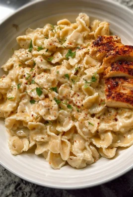 Creamy white sauce pasta topped with herbs and cheese in a bowl