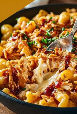 Delicious shredded BBQ chicken mac and cheese topped with cheese and BBQ sauce