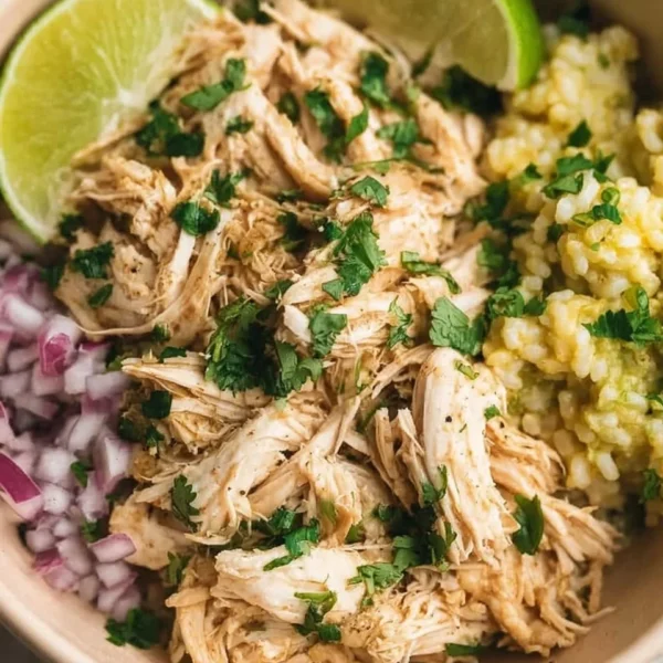 Delicious shredded slow cooker cilantro lime chicken served in a bowl with fresh toppings.