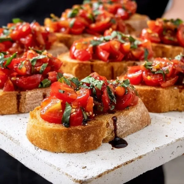 Delicious tomato bruschetta topped with fresh basil and balsamic glaze.
