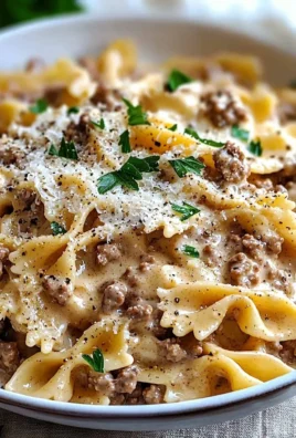 A bowl of creamy beef pasta garnished with herbs and cheese