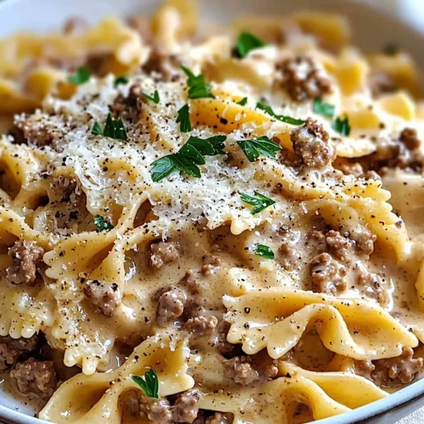 A bowl of creamy beef pasta garnished with herbs and cheese