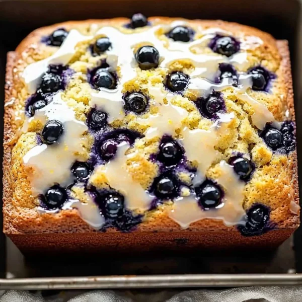 Slice of lemon blueberry bread drizzled with lemon glaze on a plate