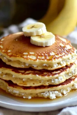 Fluffy banana cottage cheese pancakes stacked on a plate with syrup