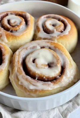 Delicious homemade cinnamon rolls topped with icing on a wooden table