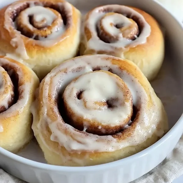 Delicious homemade cinnamon rolls topped with icing on a wooden table