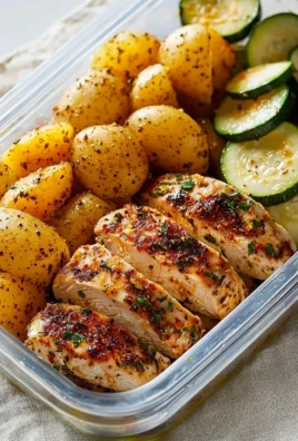 Lemon garlic chicken meal prep with fresh herbs and lemon slices.