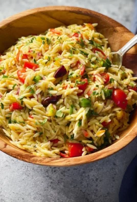 Colorful orzo pasta salad with vegetables and herbs in a bowl