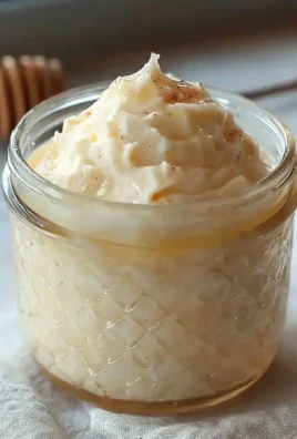 A jar of whipped honey with a wooden dipper, showcasing its creamy texture.