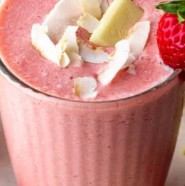 A refreshing Bahama Mama Tropical Smoothie in a coconut shell with tropical fruit slices.