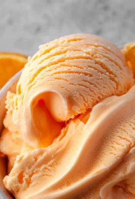 Delicious homemade orange ice cream served in a bowl with a scoop.