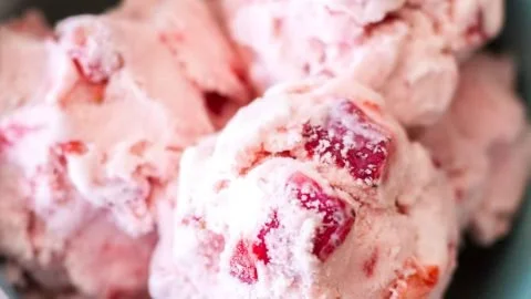 Bowl of homemade strawberry ice cream topped with fresh strawberries
