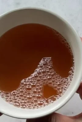 A cup of Korean Apple Tea with apple slices and spices