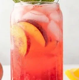 A refreshing Raspberry Peach Lemonade Cooler served in a glass with ice and mint leaves.