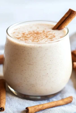 Vanilla Cinnamon Roll Protein Smoothie in a glass, topped with cinnamon and vanilla.