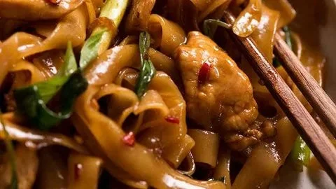 Plate of colorful drunken noodles with vegetables and shrimp