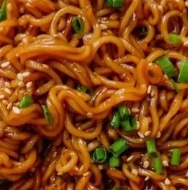Plate of easy saucy ramen noodles garnished with vegetables and herbs