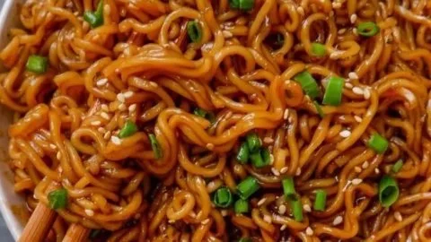 Plate of easy saucy ramen noodles garnished with vegetables and herbs