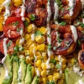 Grilled shrimp bowl with fire-roasted corn and creamy lime crema garnished with lime.