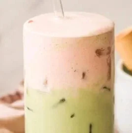 Iced Strawberry Matcha Latte in a glass with strawberries and matcha powder.