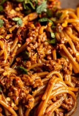 Bowl of spicy Korean Gochujang noodles with fresh veggies and garnish.