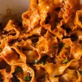 Delicious bowl of spicy peanut noodles topped with vegetables.