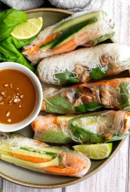 Vietnamese summer rolls with chicken served on a plate with fresh herbs and dipping sauce.