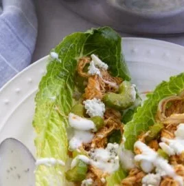 Buffalo chicken lettuce wraps garnished with green onions and served on a plate