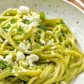 Delicious creamy Mexican green spaghetti dish topped with fresh herbs.