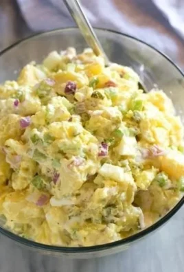 Creamy potato salad served in a bowl with fresh herbs and seasoning.