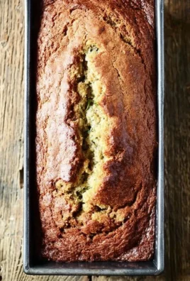 Loaf of super-moist zucchini bread garnished with walnuts on a wooden cutting board.