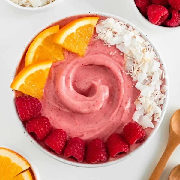 Delicious Raspberry Orange Smoothie Bowl topped with fresh fruits and granola.