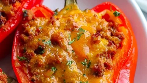 Sloppy Joe stuffed peppers topped with cheese and fresh herbs on a plate