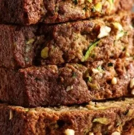 Slice of moist zucchini bread with toasted nuts on a plate